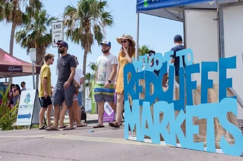 Redcliffe Jetty Markets, sign with locals and tourits beside the sign