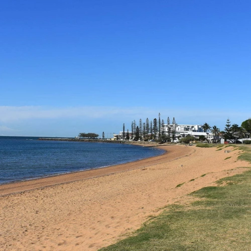 Image of North Queens Beach's blue ocean, sand, by the grass and park
